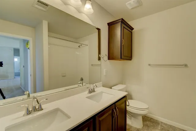 a bathroom with a granite countertop sink toilet and mirror