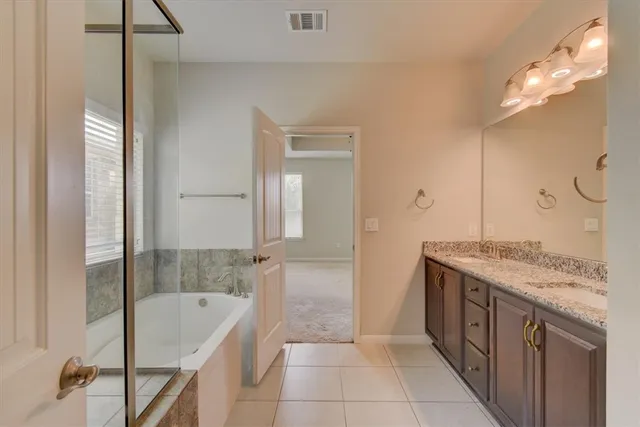 a spacious bathroom with a granite countertop sink a mirror and a bathtub