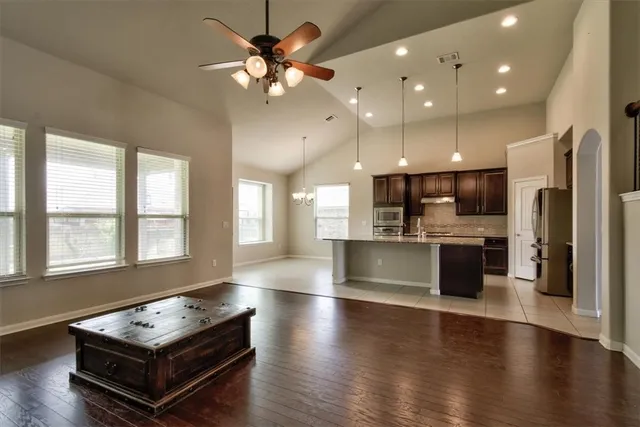 an open kitchen with kitchen island a large counter top stainless steel appliances and a chandelier