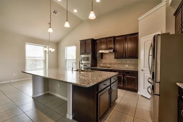a kitchen with stainless steel appliances granite countertop a sink a stove and a refrigerator