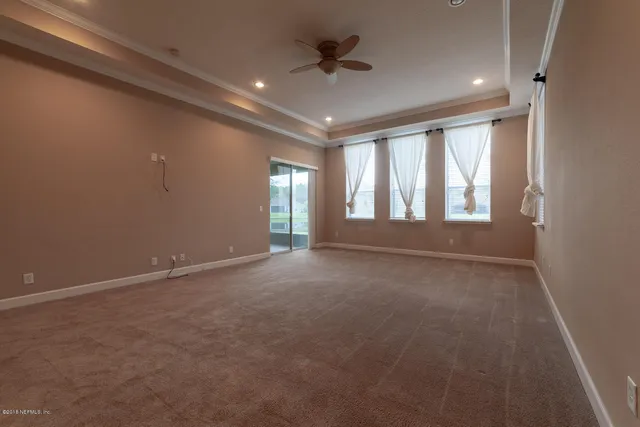 an empty room with a ceiling fan and windows