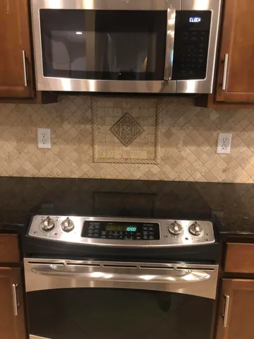 a kitchen with kitchen island granite countertop cabinets and stainless steel appliances