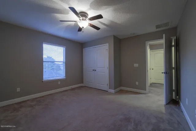 an empty room with windows and fan