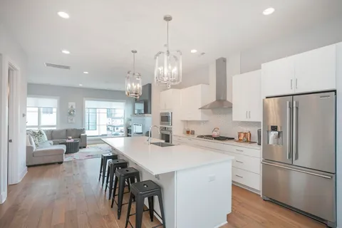 a kitchen with refrigerator a center island wooden floor and living room view