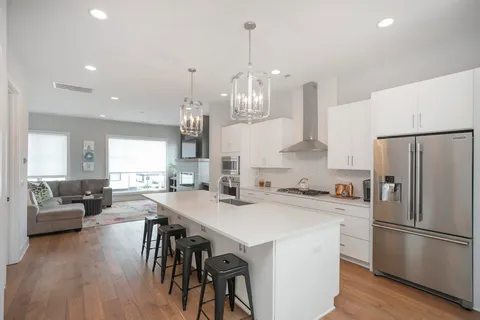 a kitchen with stainless steel appliances a dining table chairs stove refrigerator and cabinets