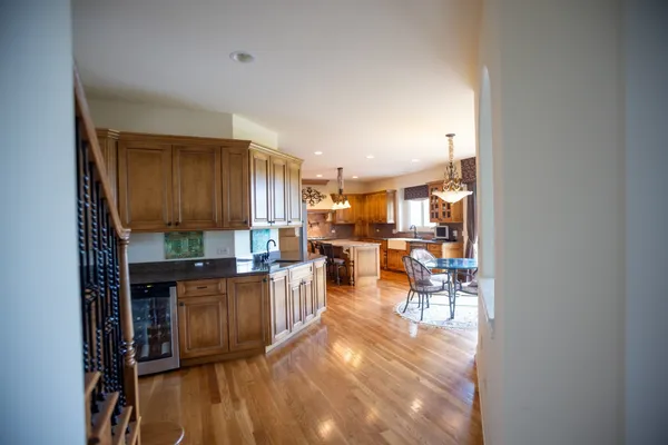a kitchen with stainless steel appliances granite countertop a refrigerator a stove top oven a dining table and chairs with wooden floor