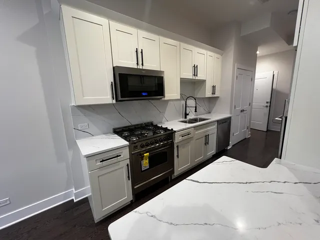 a kitchen with stainless steel appliances white cabinets a sink and a stove