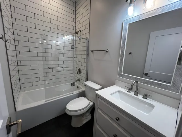 a bathroom with a bathtub shower sink mirror and toilet