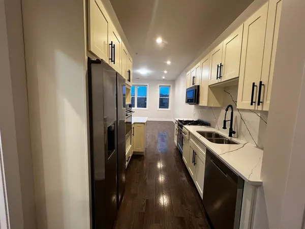 a kitchen with a sink stainless steel appliances a counter top space and cabinets