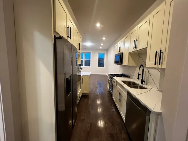 a kitchen with a sink stainless steel appliances a counter top space and cabinets
