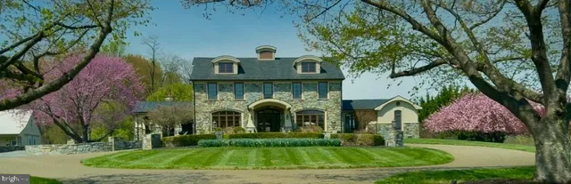 a front view of a house with garden and trees