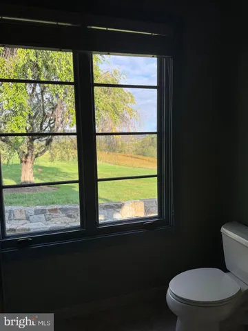a living room with furniture hard wood floor and a floor to ceiling window