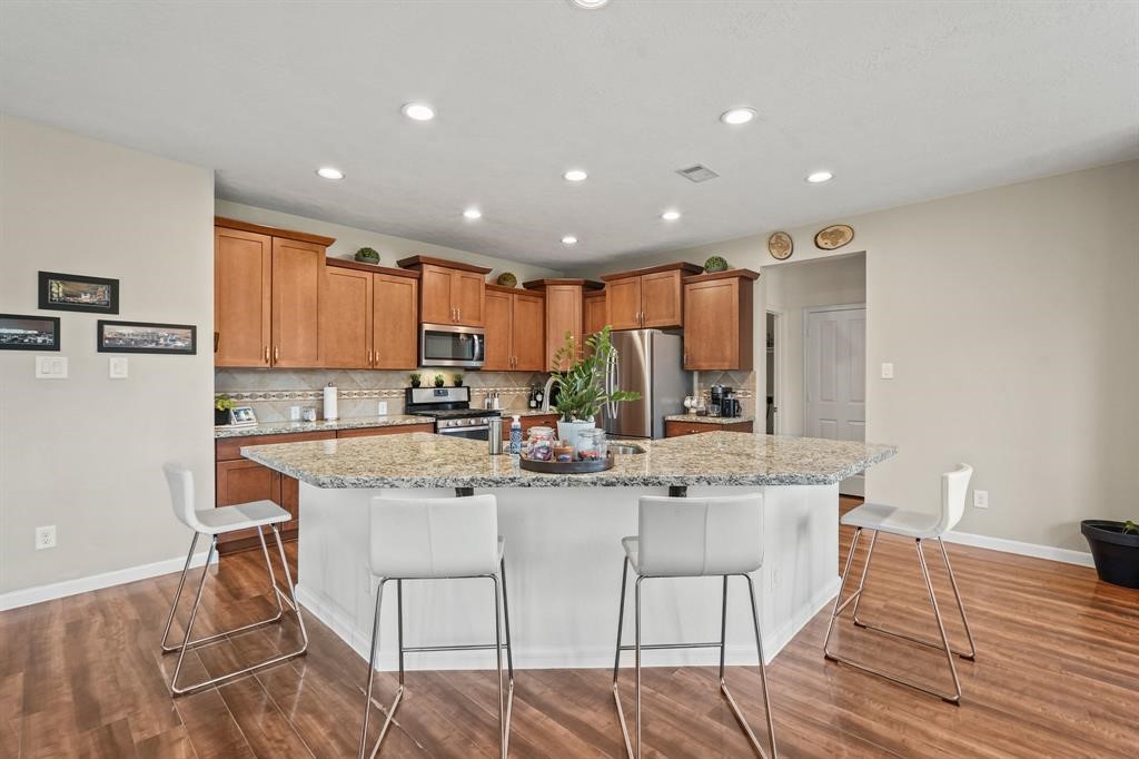 6719 Path Way Court Katy, TX 77449 - Photo 13 of 35 a kitchen with stainless steel appliances granite countertop a stove a sink a refrigerator and a dining table with wooden floor