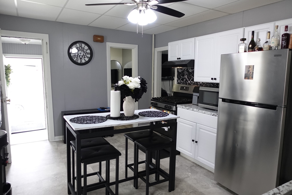 5 Vernon Street Holyoke, MA 01040 - Photo 6 of 12 a kitchen with stainless steel appliances granite countertop a dining table chairs and refrigerator