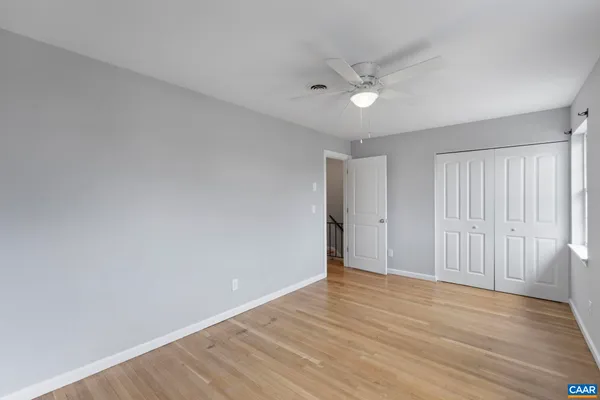 a view of an empty room with a window and wooden floor