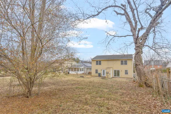 a view of a white house next to a large tree
