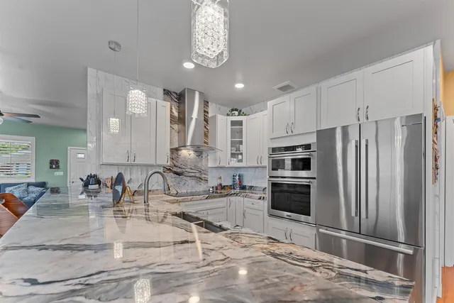 a kitchen with stainless steel appliances granite countertop a sink refrigerator and cabinets