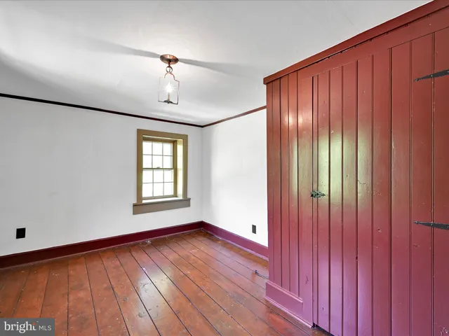 an empty room with wooden floor chandelier and windows