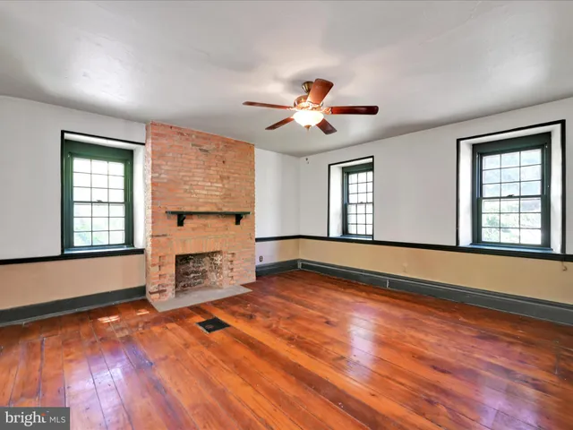 a view of an empty room with window and wooden floor