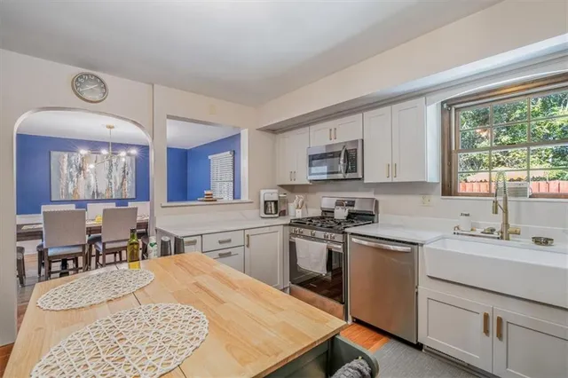 a kitchen with a stove a sink dishwasher a refrigerator cabinets and dining table