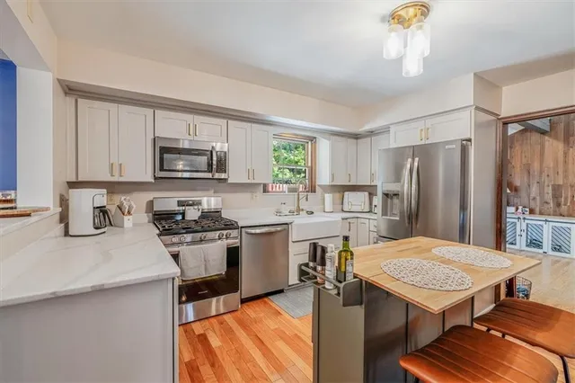 a kitchen with stainless steel appliances granite countertop white cabinets sink and window