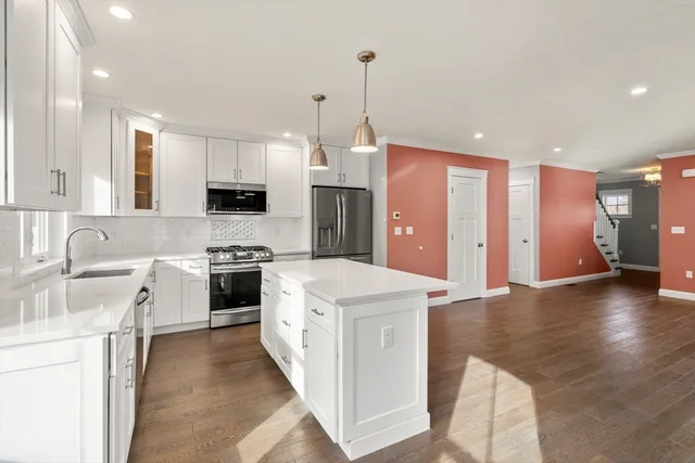 a kitchen with stainless steel appliances kitchen island granite countertop a stove top oven a sink dishwasher and a refrigerator with wooden floor