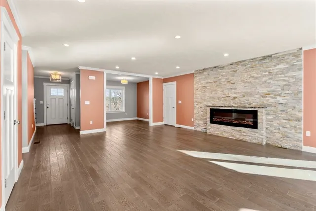 an empty room with wooden floor fireplace and windows