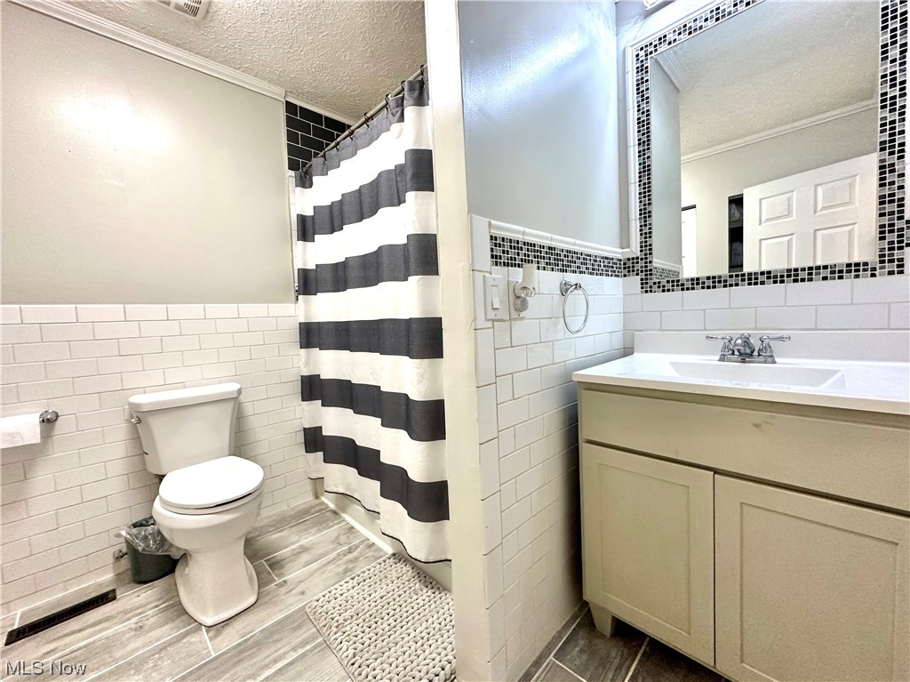 444 Eyermann Road Belpre, OH 45714 - Photo 10 of 16 Bathroom featuring tile walls, a textured ceiling, tile flooring, tasteful backsplash, and large vanity