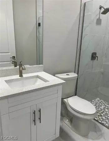 a bathroom with a granite countertop toilet sink and mirror