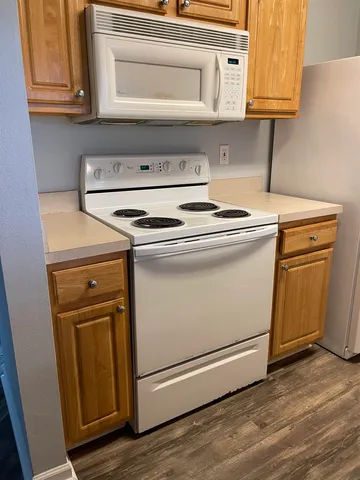a stove top oven sitting inside of a kitchen with granite countertop cabinets and wooden floor