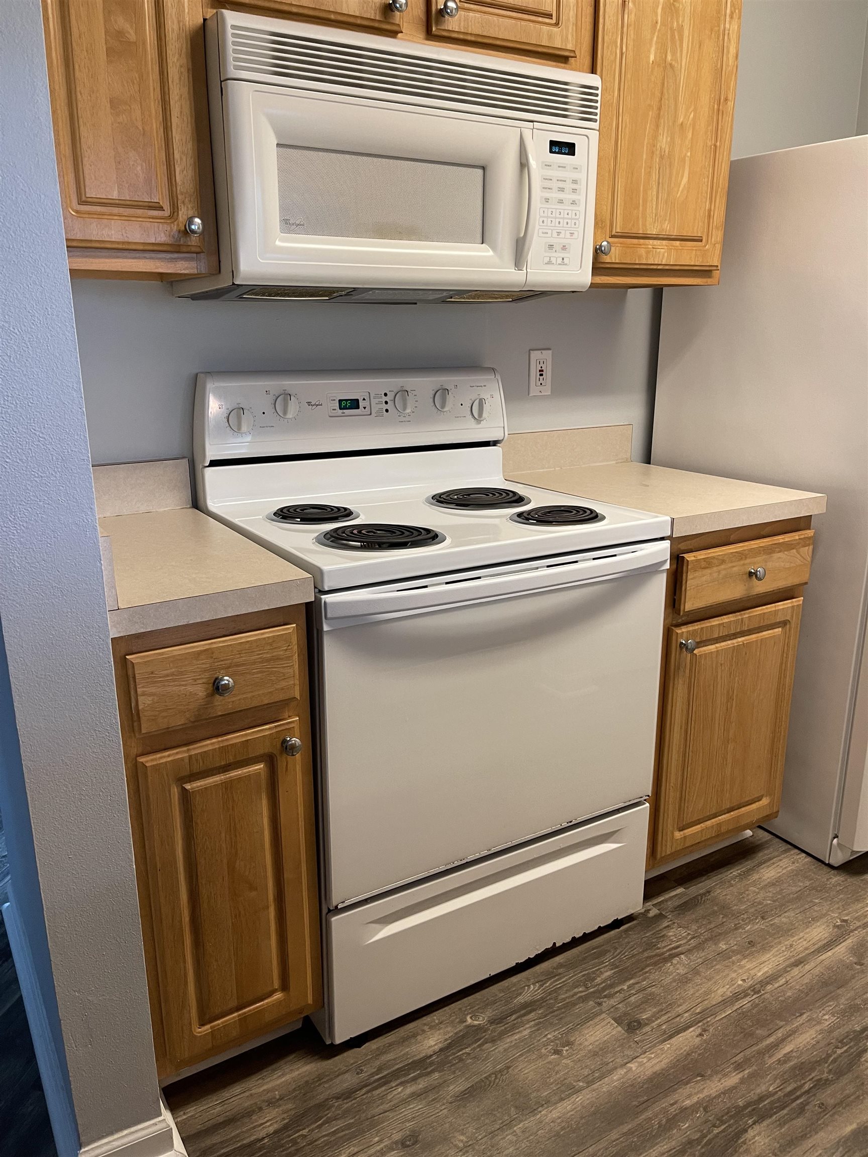 4035 Grande Vista Boulevard, Unit 201 St. Augustine, FL 32084 - Photo 8 of 28 a stove top oven sitting inside of a kitchen with granite countertop cabinets and wooden floor