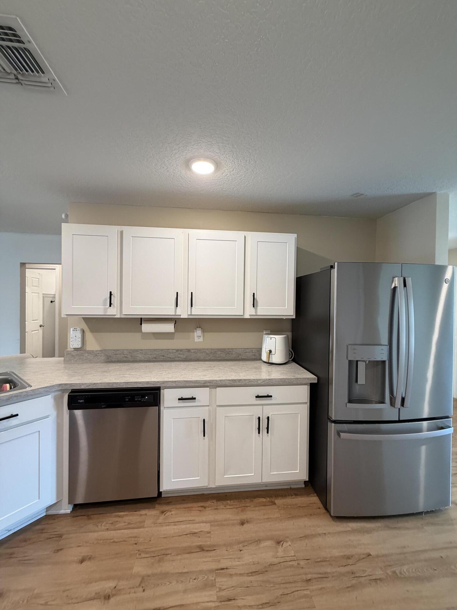 4249 Southwest Whitebread Road Port St. Lucie, FL 34953 - Photo 13 of 43 a kitchen with stainless steel appliances granite countertop a sink a stove a refrigerator and island with wooden floor
