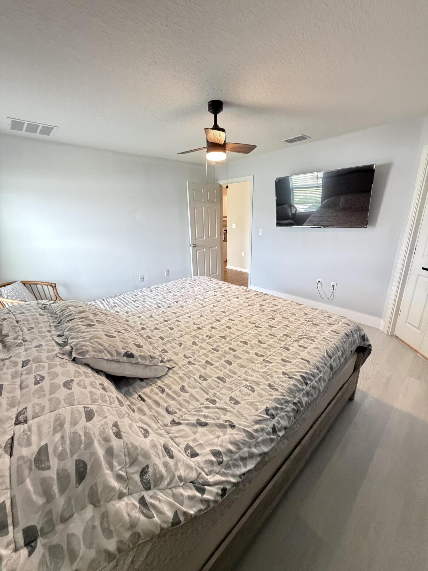 4249 Southwest Whitebread Road Port St. Lucie, FL 34953 - Photo 19 of 43 a bedroom with a large bed and a flat screen tv