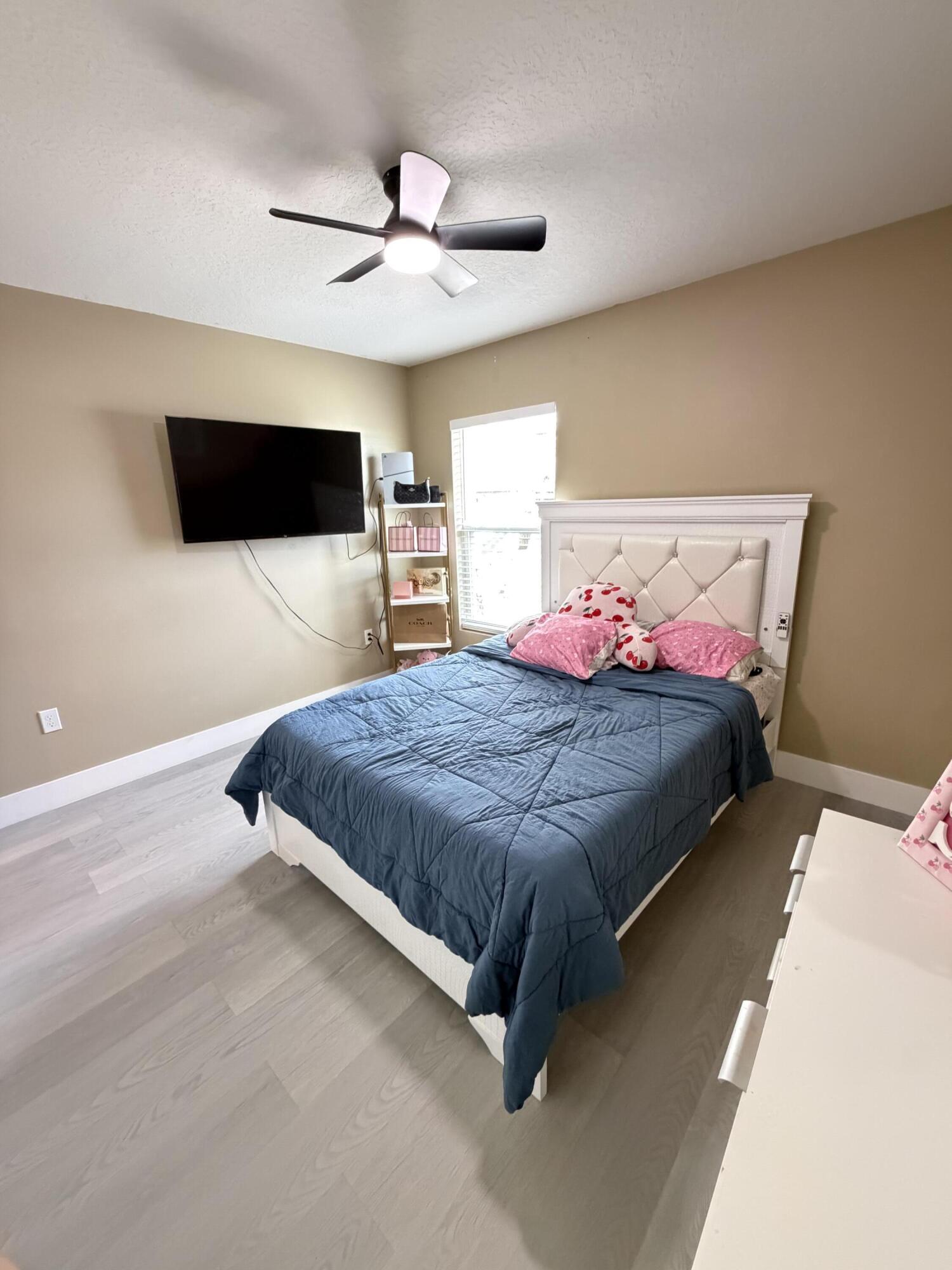 4249 Southwest Whitebread Road Port St. Lucie, FL 34953 - Photo 28 of 43 a bedroom with a bed a flat screen tv and a chandelier