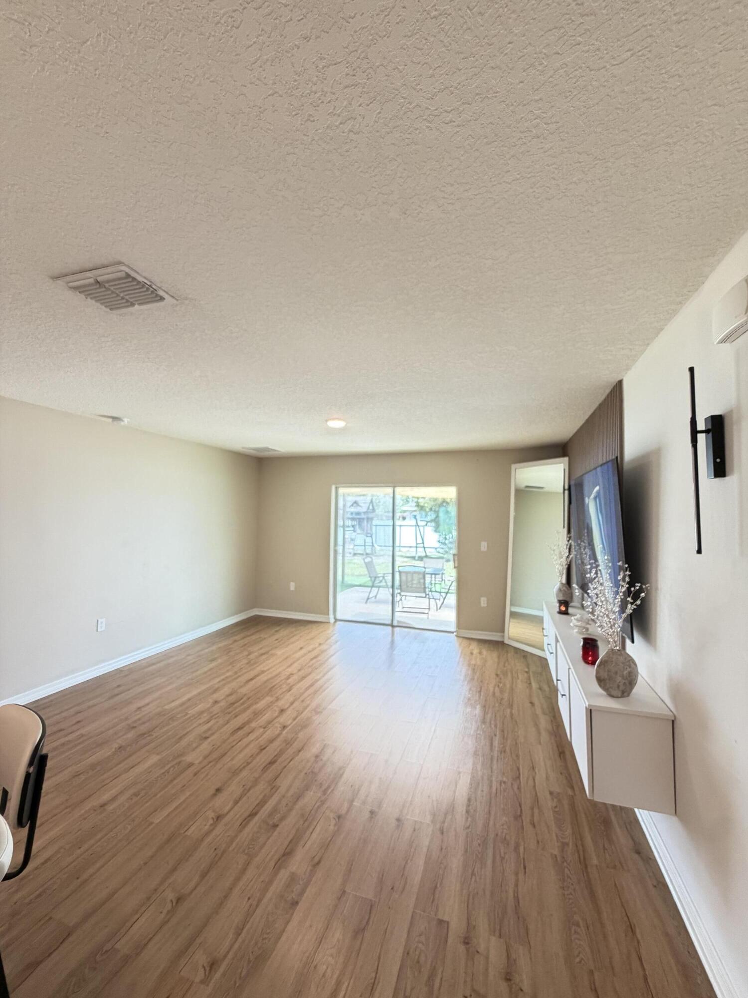 4249 Southwest Whitebread Road Port St. Lucie, FL 34953 - Photo 3 of 43 a view of a livingroom with wooden floor and a flat screen tv