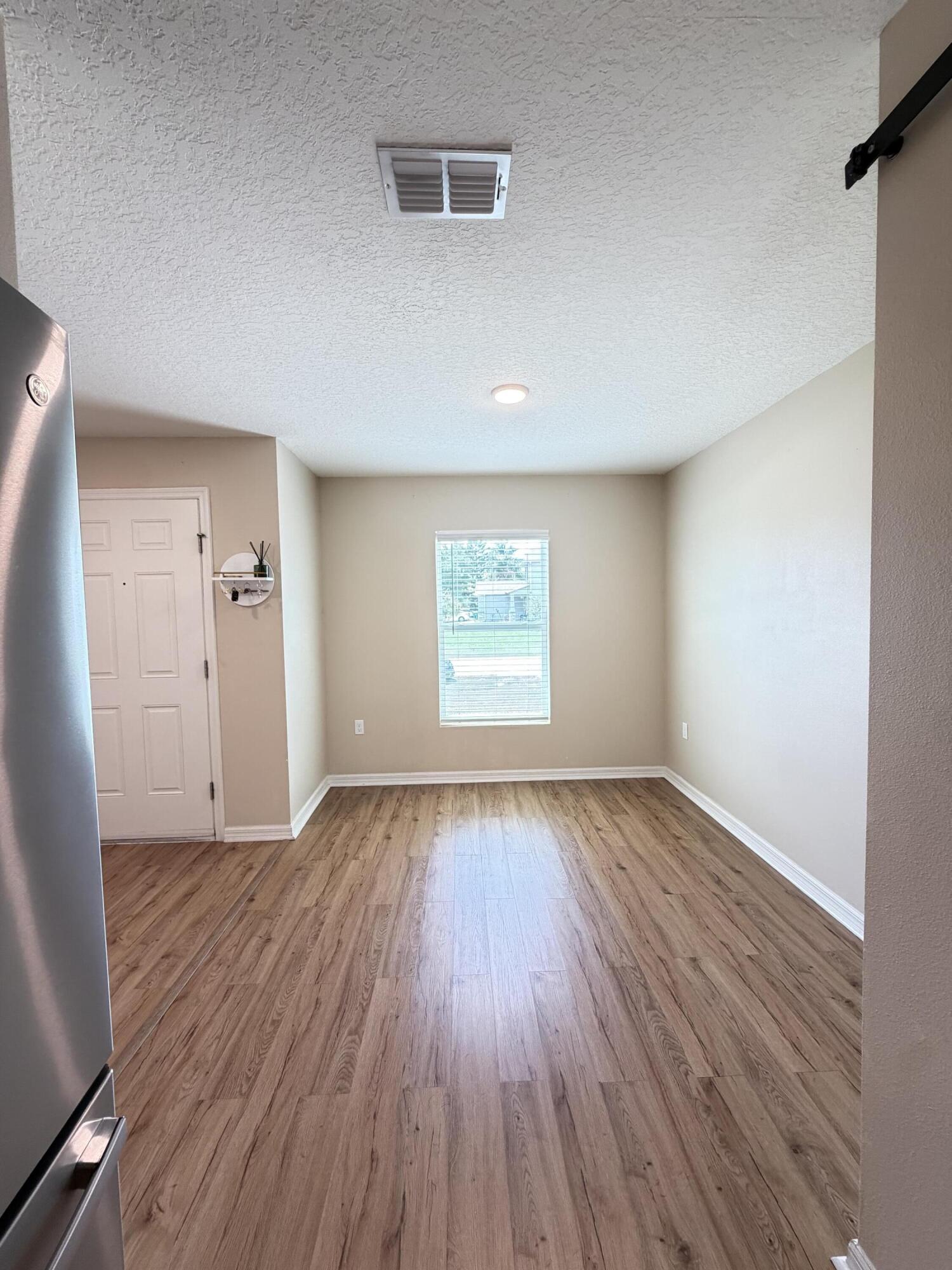 4249 Southwest Whitebread Road Port St. Lucie, FL 34953 - Photo 9 of 43 an empty room with wooden floor and windows