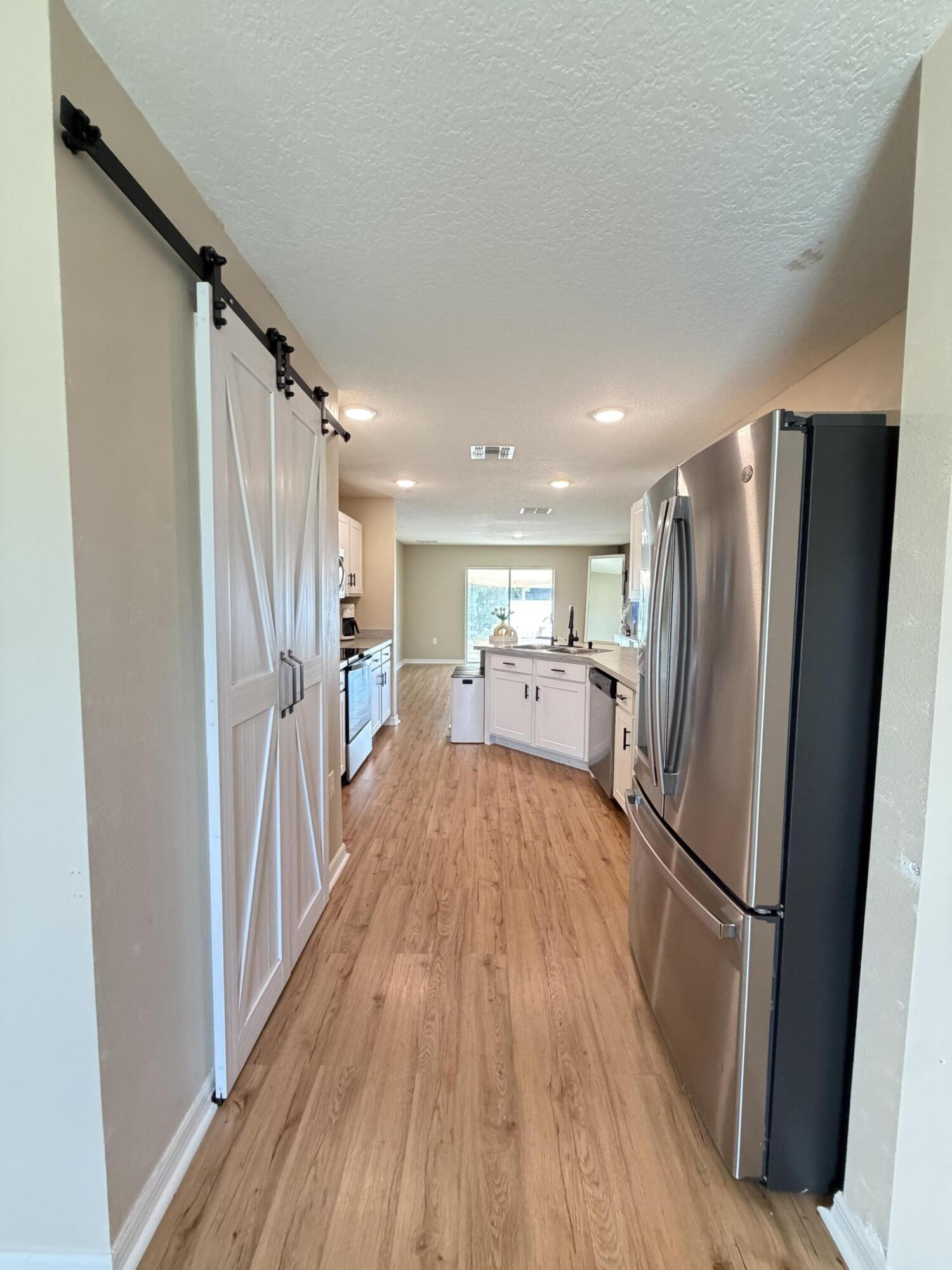 4249 Southwest Whitebread Road Port St. Lucie, FL 34953 - Photo 10 of 43 a view of a refrigerator in kitchen and wooden floor
