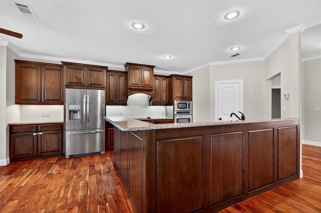357 Pear Tree Lane Collinsville, TX 76233 - Photo 16 of 37 a kitchen with stainless steel appliances granite countertop a refrigerator and wooden cabinets