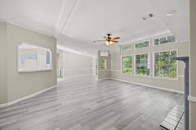a view of an empty room with a window and wooden floor