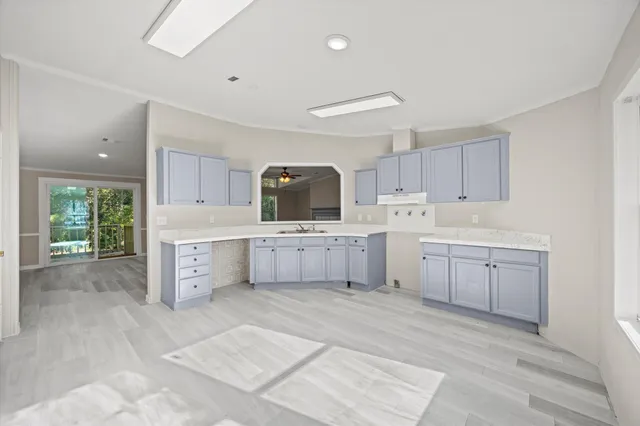 a large white kitchen with a stove a sink a window and cabinets