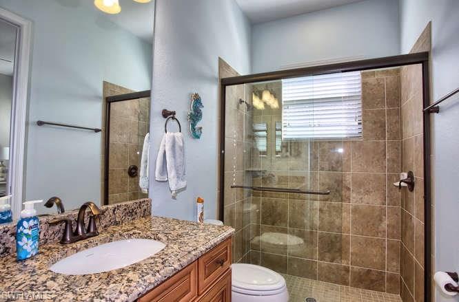 9633 Firenze Circle Naples, FL 34113 - Photo 12 of 25 a bathroom with a granite countertop sink toilet a mirror and shower