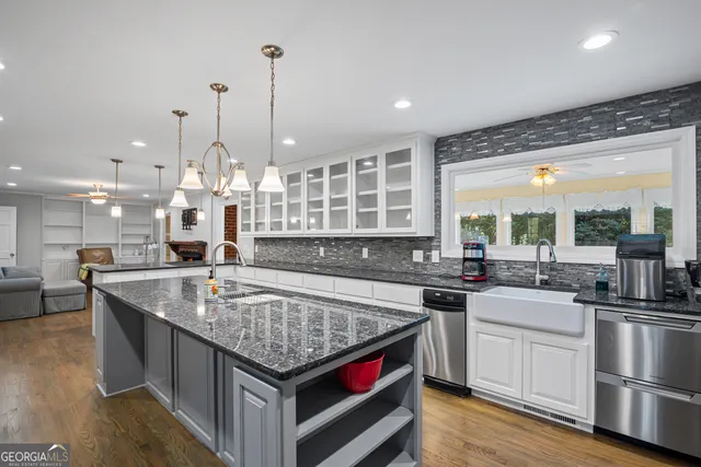 a kitchen with kitchen island granite countertop a sink a center island and wooden floor