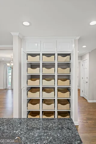 a view of an empty room and kitchen with wooden floor