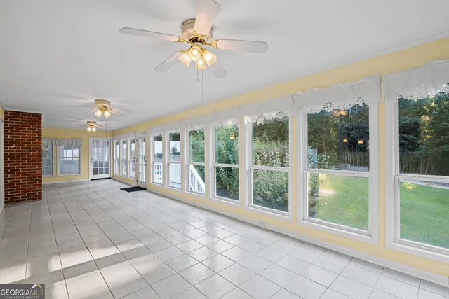 a view of an empty room with a window and chandelier fan