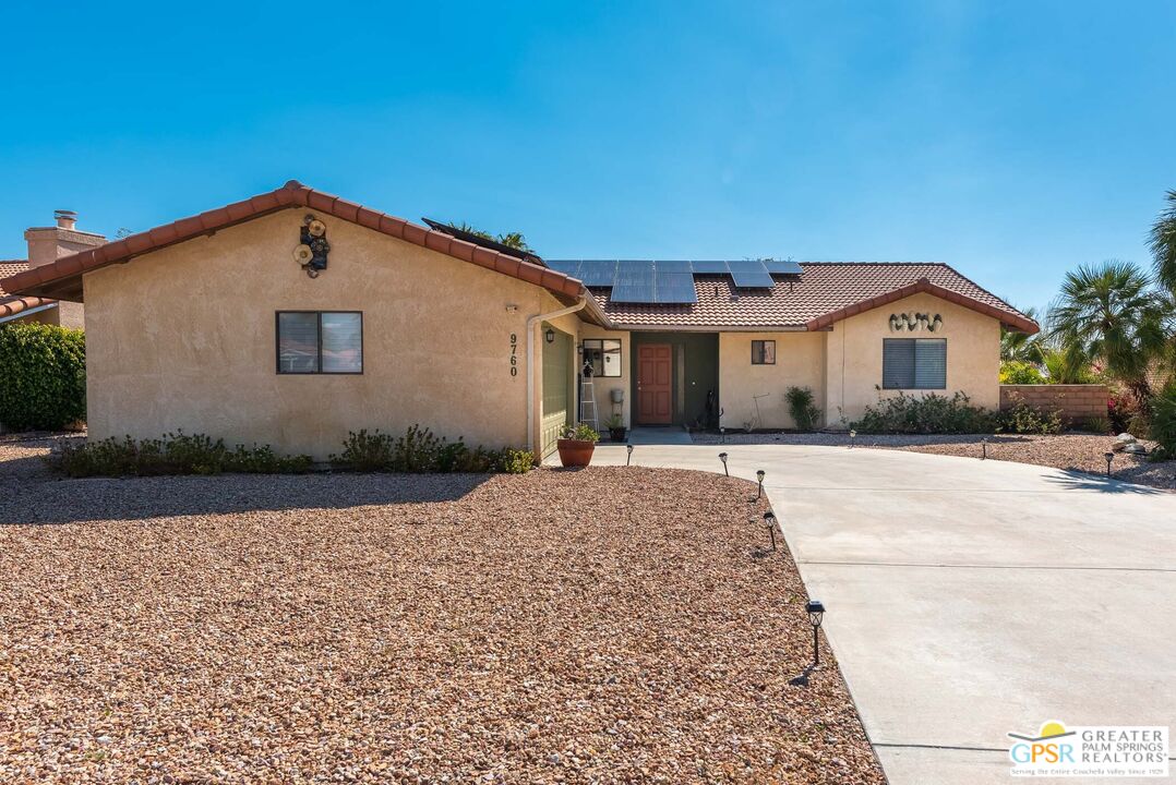 9760 Capiland Road Desert Hot Springs, CA 92240 - Photo 1 of 16 a front view of a house with a yard and garage