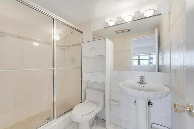 a bathroom with a shower sink vanity mirror and toilet