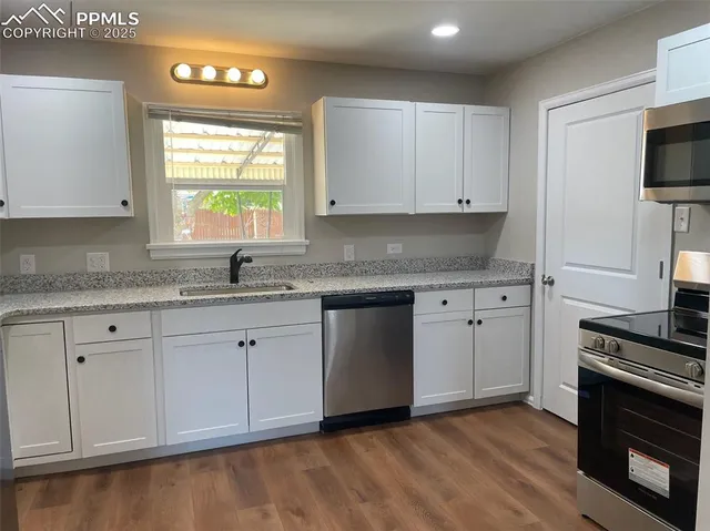 a kitchen with granite countertop a stove a sink and a microwave