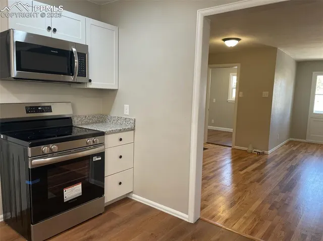 a kitchen with stainless steel appliances a stove a microwave oven cabinets and wooden floor