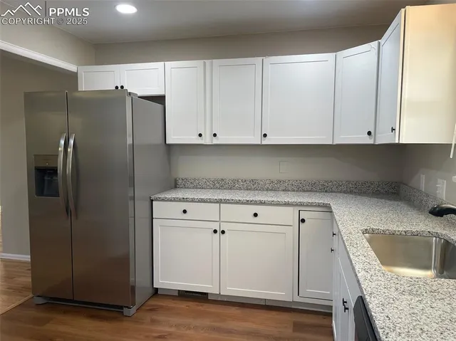 a kitchen with granite countertop a refrigerator sink and cabinets