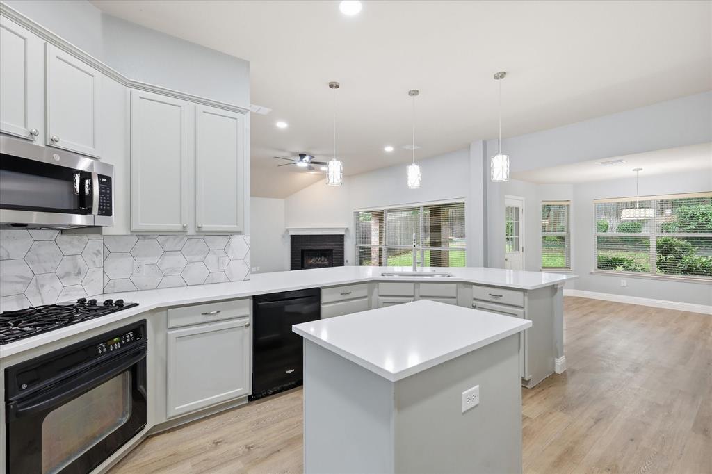 2616 Hollow Ridge Drive Denton, TX 76210 - Photo 13 of 31 Contemporary kitchen featuring a large island, white countertops, hexagon tile backsplash, stainless steel microwave, and wood-finish flooring